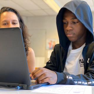 Student and his teacher behind a laptop