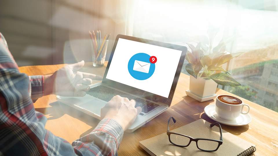 Man leest e-mail op laptop in een zonnig kantoor