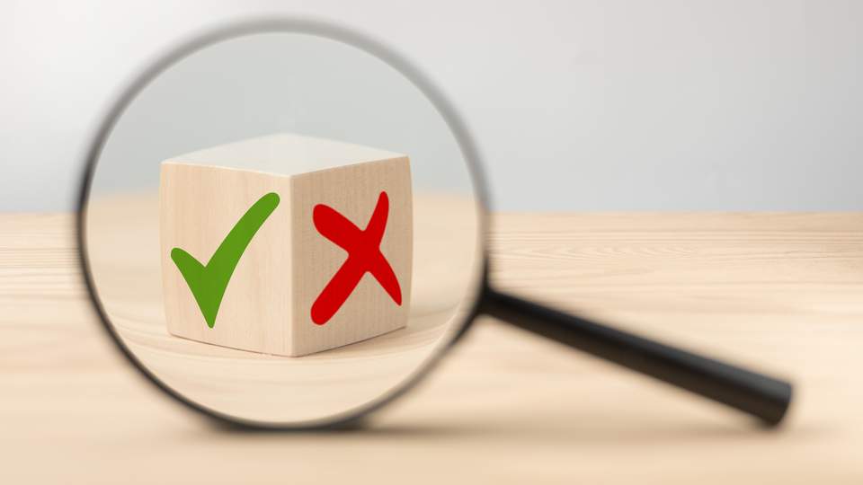 Illustratie van een vergrootglas dat een vinkje of kruis bekijkt.