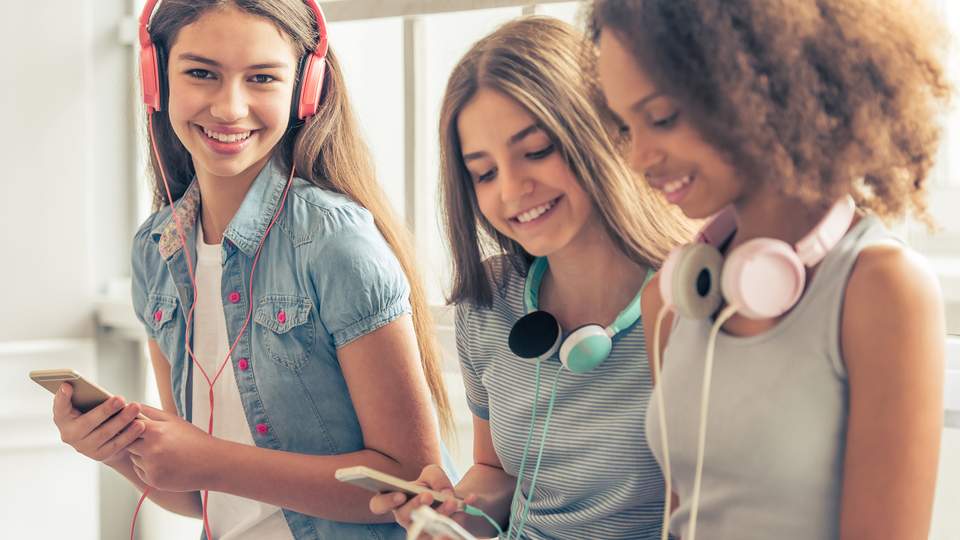 Teenage girls on their smartphones, using headsets